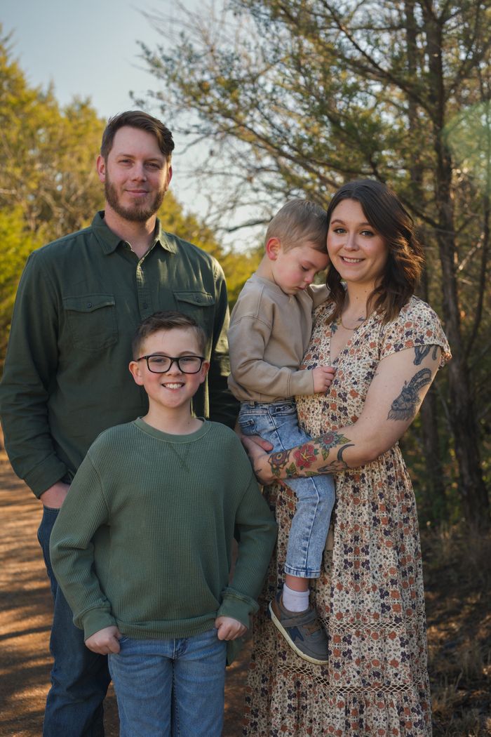 A joyful family posing outdoors in an autumn forest setting. Perfect for seasonal and lifestyle themes.