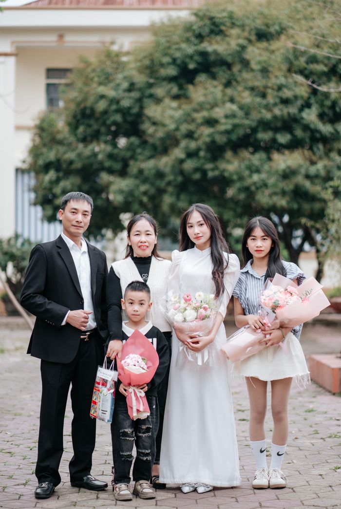 Family portrait with three adults and two kids holding gifts outdoors.
