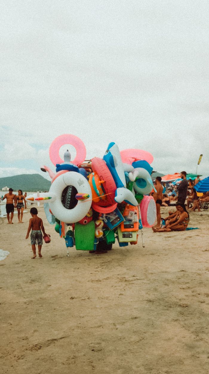Busy beach scene featuring colorful inflatable floats and beachgoers enjoying a sunny day.