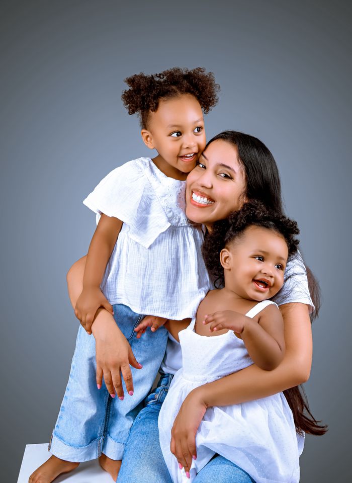 Joyful family portrait capturing a mother bonding with her two daughters, smiling warmly.