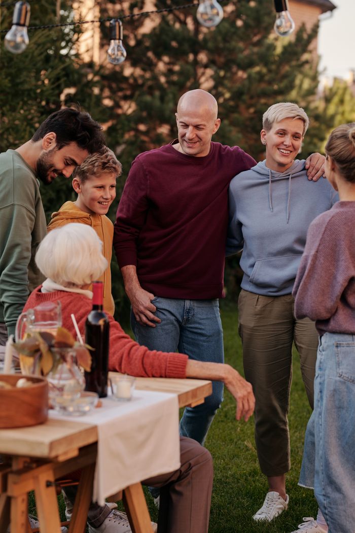 Happy family members talking and laughing while having picnic on backyard in sunny day